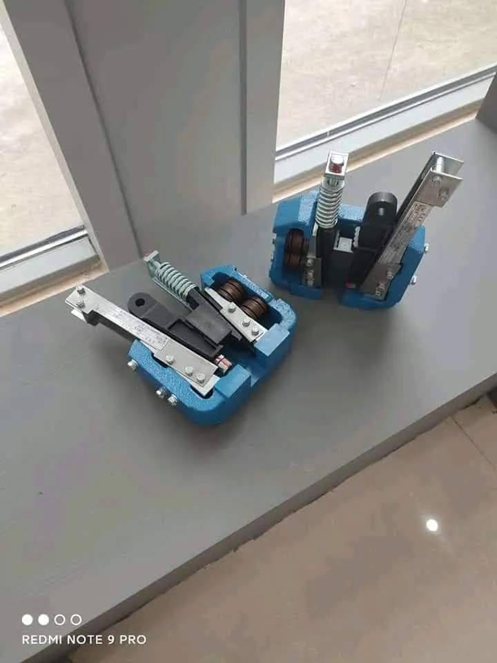 Two blue cast-body progressive safety gear units with roller wedge stacks and trip levers ready for car sling installation in Karachi