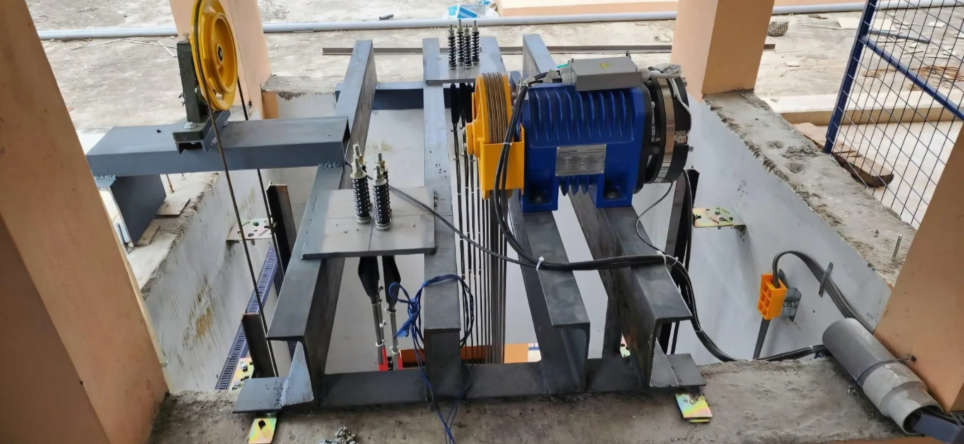 Gearless traction machine installed on machine-beam with governor, buffer springs and steel wire ropes