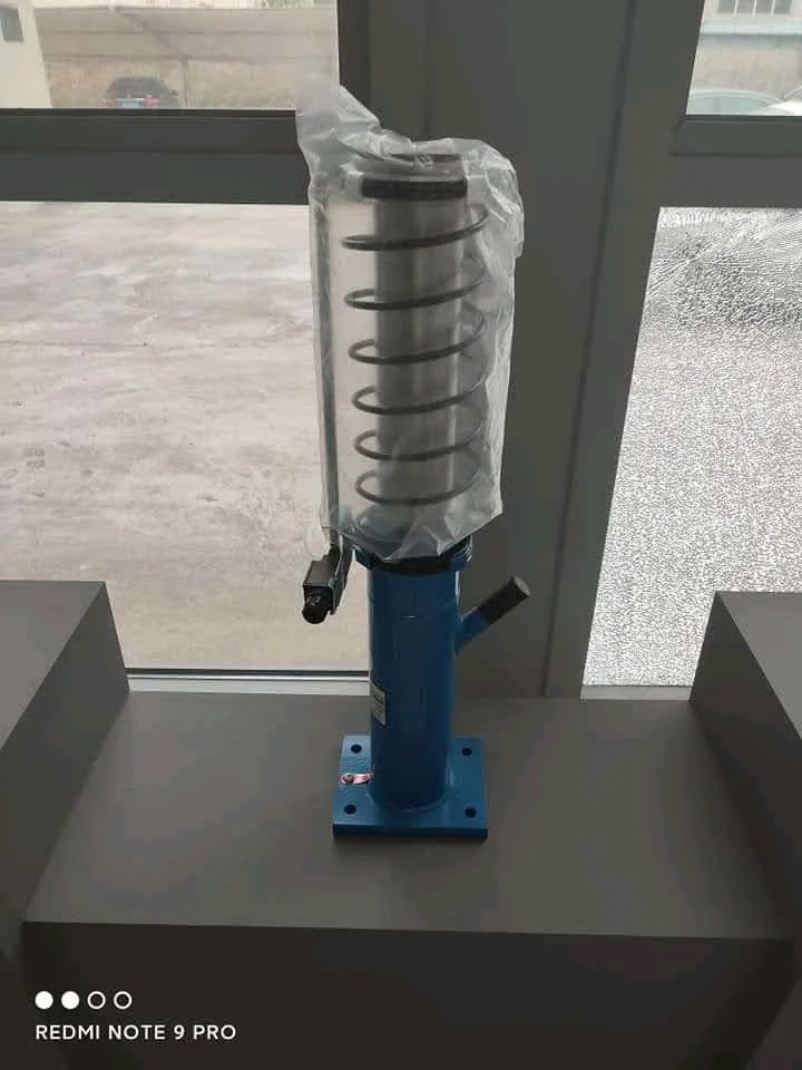 Factory-packed oil hydraulic elevator buffer with protective wrapping over the return spring, blue cylinder, oil filler port and four-hole mounting flange ready for shipment to Lahore